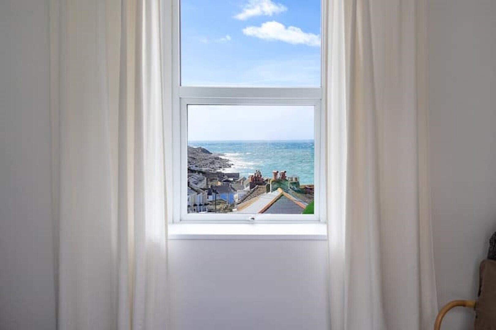 A room with a window overlooking a coastal town.