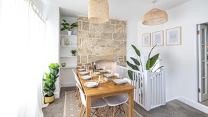 Espaço de refeições com parede de pedra, corrimão branco e luminárias pendentes.