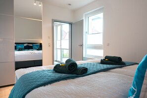 Ein modernes Schlafzimmer mit einem großen Bett, einem Einbauschrank und einem Fenster, das für natürliches Licht sorgt.