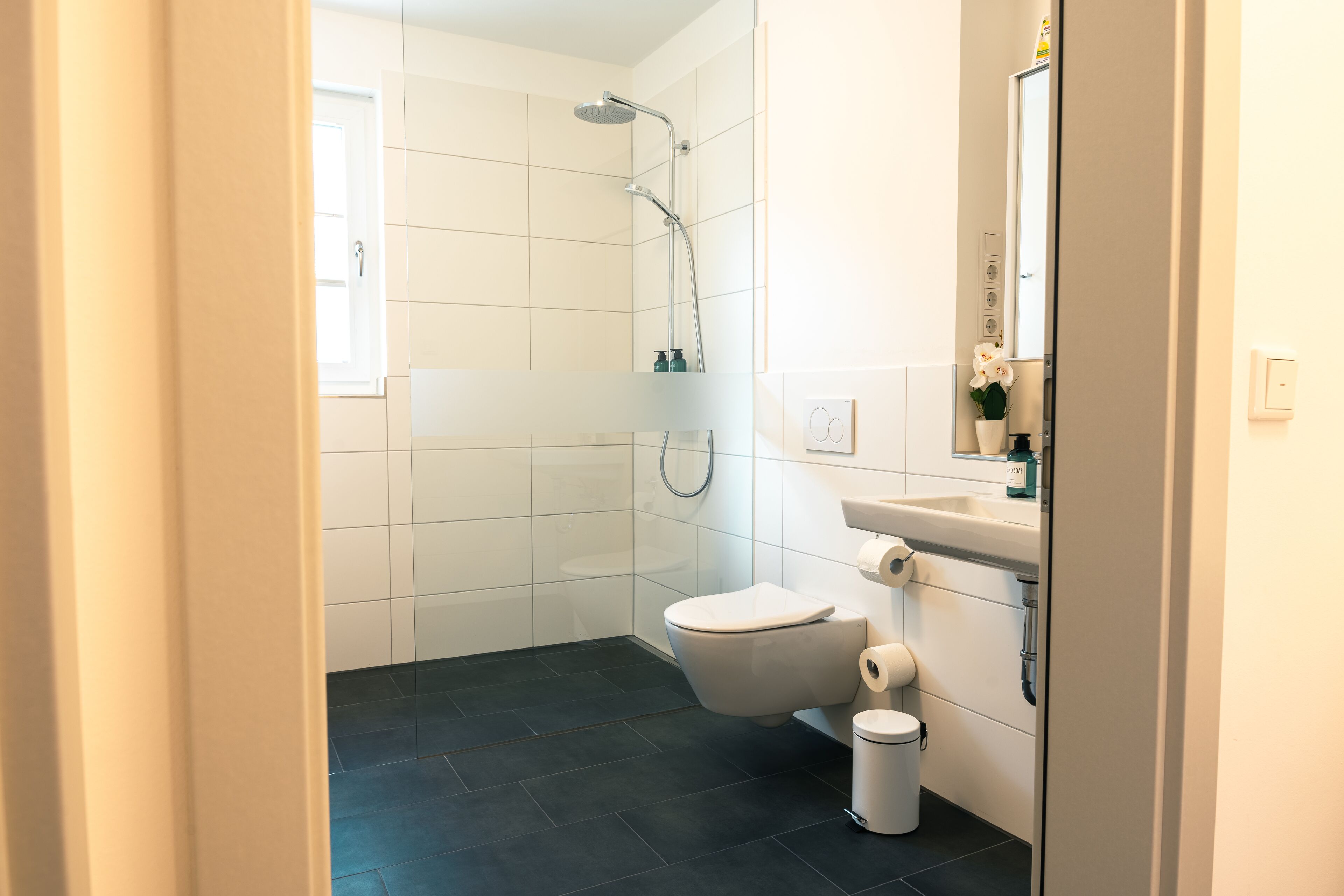 A modern bathroom with a shower, toilet, and sink.