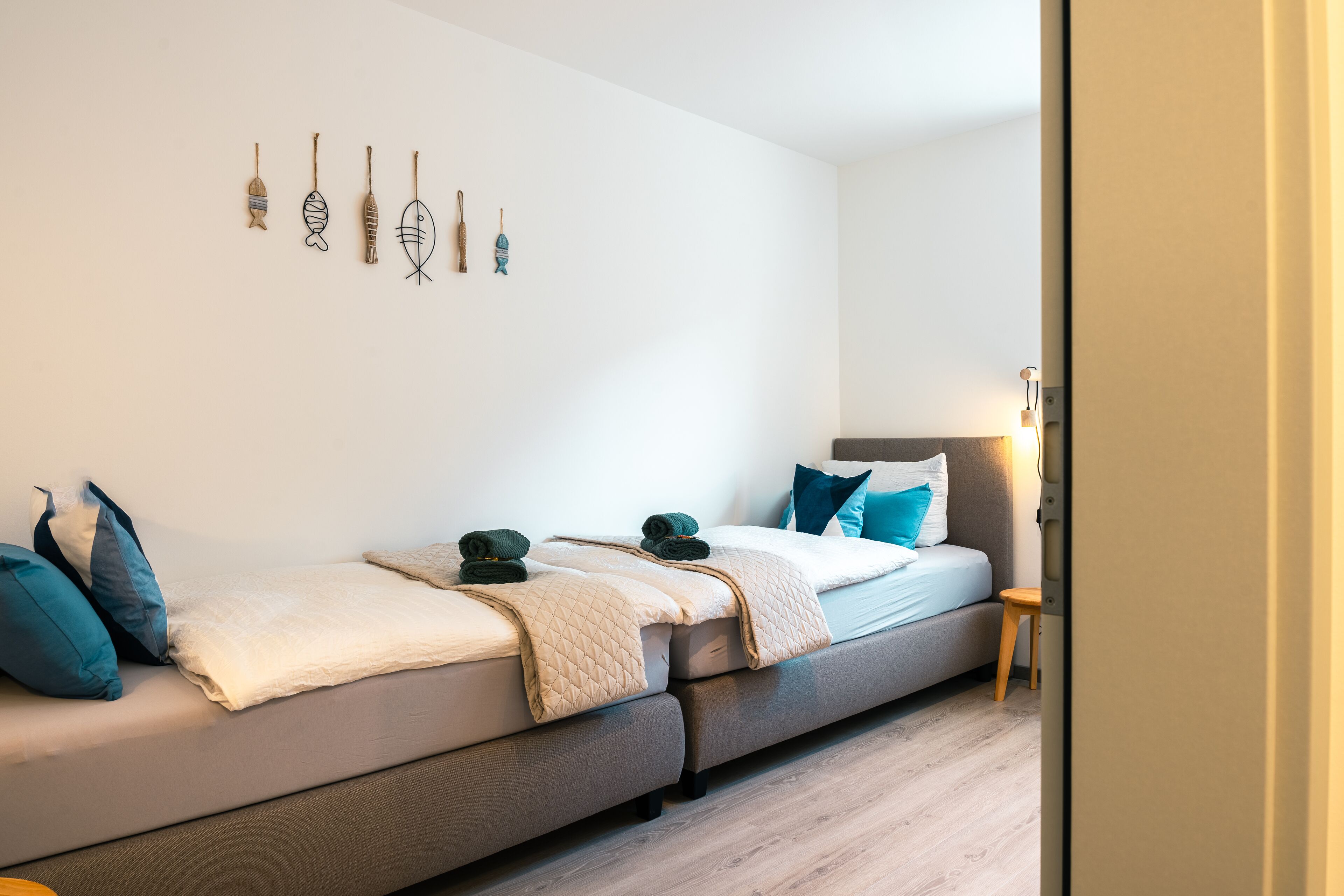 A modern bedroom with a sofa bed, a bedside table, and wall art.