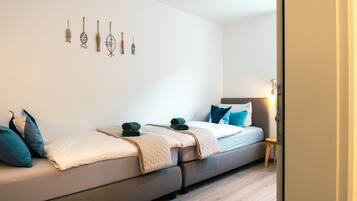A modern bedroom with a sofa bed, a bedside table, and wall art.