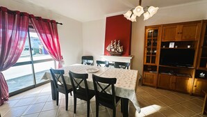 A dining area with a table set for four, chairs, a ship model, a television, and wooden cabinets. - Charles Beach House (Ferrel)