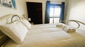 A double bed with white linens, a headboard, and a bedside table with a lamp. - Charles Beach House (Ferrel)