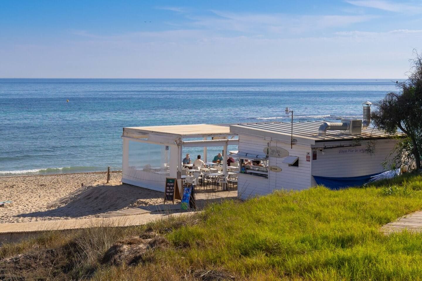 Ein Restaurant direkt am Strand mit Außenbereich, überdachten Sitzplätzen und Meerblick.