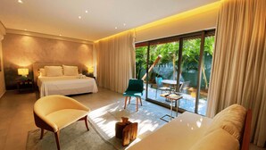 A modern hotel room with a large bed, a sitting area with a chair and a table, and a balcony with a view of greenery. - Flat Ilê de Pipa Tulum - By Almare (Tibau do Sul)