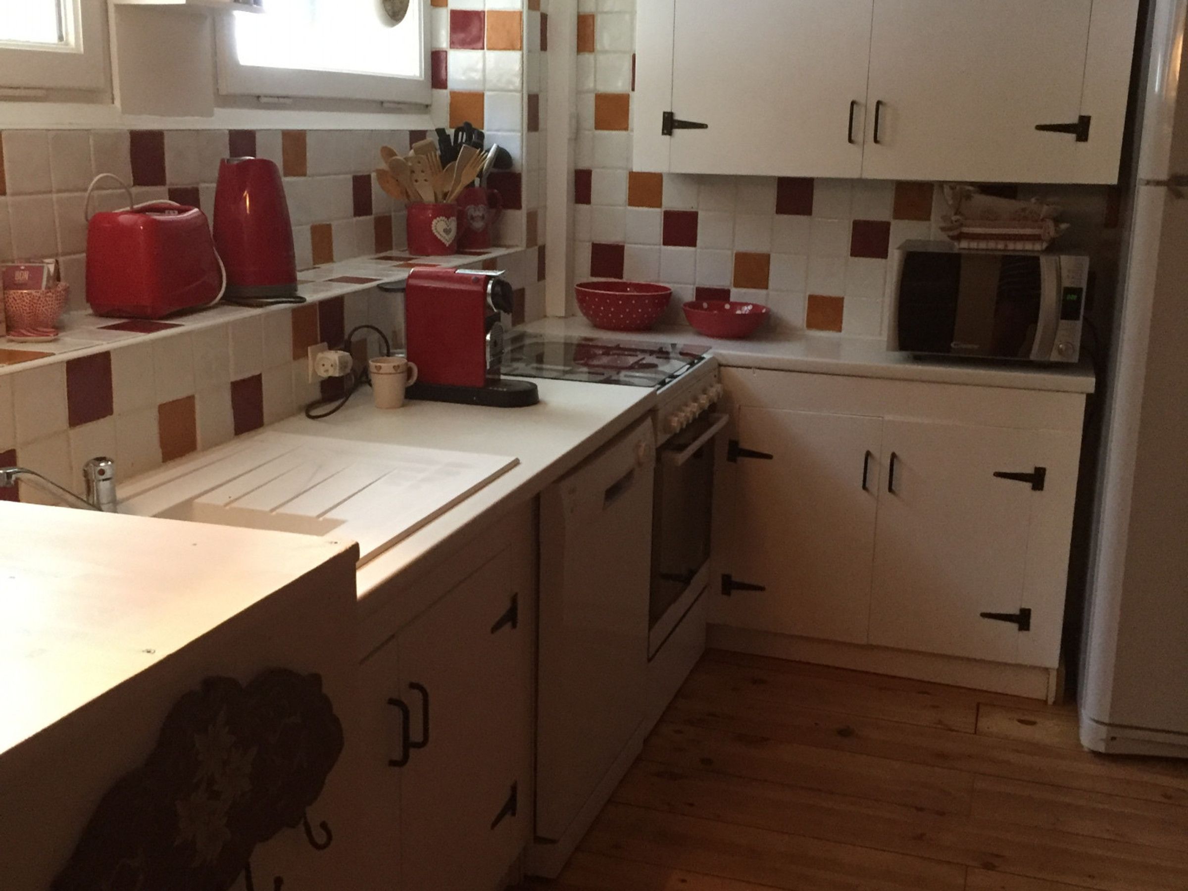 Een keuken met witte kastjes, een magnetron en een fornuis.