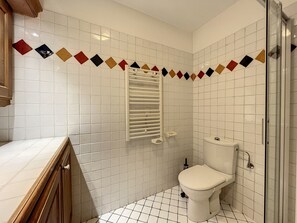 Bathroom features a toilet, shower with glass door, and storage cabinet.