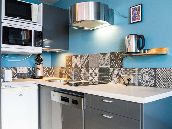 Cocina compacta con lavavajillas, cafetera y microondas.