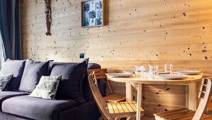 Una habitación acogedora con una pared de madera, un sofá púrpura y una mesa redonda de madera dispuesta para comer.