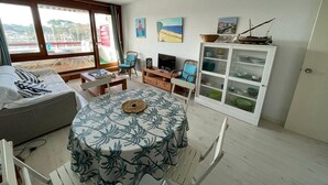 Ein gemütlicher Wohnbereich mit einem runden Tisch, zwei Sofas, einem Fernseher und einer Speisekammer mit Geschirr.