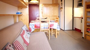 Una habitación compacta con mesa de comedor, sillas, sofá y kitchenette.