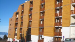 Un edificio de varios pisos con un diseño moderno, que cuenta con balcones en cada planta.