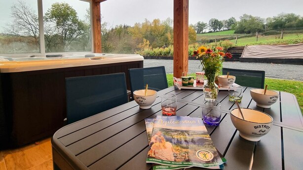 Un tavolo con idromassaggio, sedie, un vaso con fiori e una brochure.