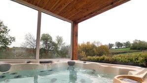 Una vasca idromassaggio con tetto in legno e ampie finestre vista giardino.