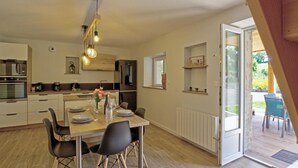 Una cucina moderna con mobili in legno, un forno integrato e un'area pranzo con tavolo apparecchiato per quattro.
