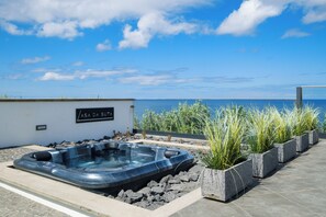Un área de jacuzzi con vista al mar, rodeada de macetas y un letrero que dice "ASA DA SUTA".