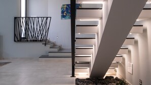 Un interior moderno con una escalera, barandilla de metal negro y un cuadro en la pared.
