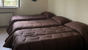 Un dormitorio con dos camas, una ventana, un radiador y un adorno en la pared.