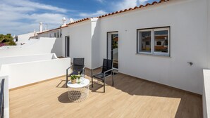Une terrasse sur le toit avec une table ronde, des chaises et un pot de fleurs.