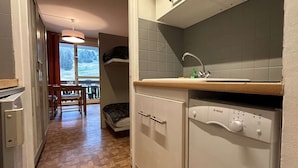 A compact kitchen with a Bosch dishwasher, a wooden countertop, and a window overlooking a snowy landscape.