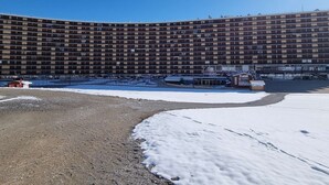 A large, multi-story hotel with a curved facade, a parking lot, and a small building in front.