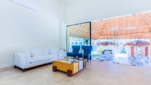 Un salon moderne avec un canapé blanc, une table basse en bois et deux fauteuils bleus.