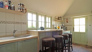 Una cucina con un'isola grande, sgabelli da bar, un lavandino e una porta verde.