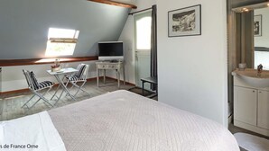 Una camera da letto con un letto, una scrivania con un computer, una sedia, una finestra e un bagno con lavandino e specchio.