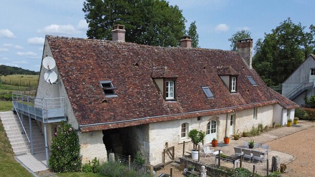 Una casa in pietra tradizionale con tetto a falde, un piccolo giardino e una scala che conduce all'ingresso.