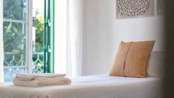 Habitación de hotel con cama, ventana que da a zonas verdes y un adorno en la pared.