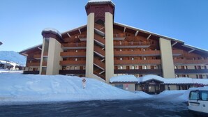 A multi-story hotel with a central tower, balconies, and a snow-covered parking area.