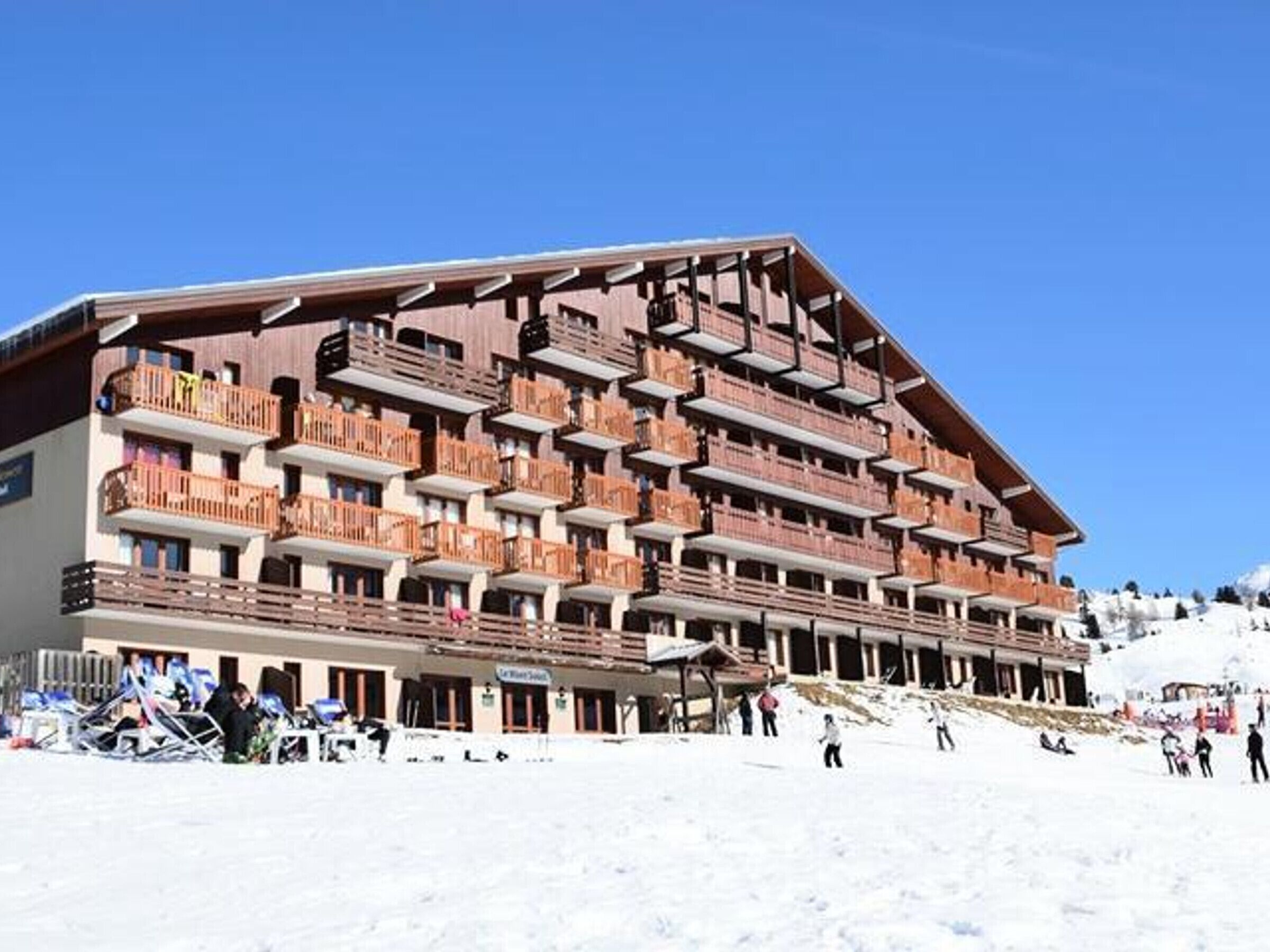 A multi-story hotel with balconies and a ski slope in the background.