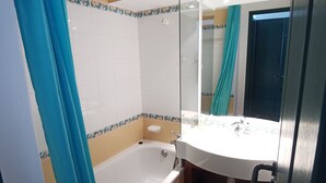 A bathroom with a bathtub, a sink, and a mirror.