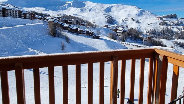 A snow-covered mountain landscape with a ski resort, including buildings and ski slopes.