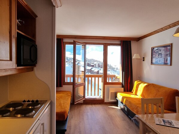 A cozy room with a bed, a table, and a kitchen area.