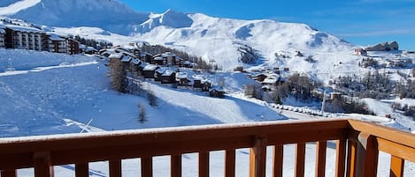 A snow-covered mountain landscape with a ski resort, including buildings and ski slopes.
