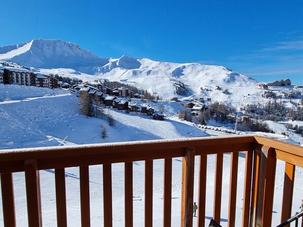 A snow-covered mountain landscape with a ski resort, including buildings and ski slopes.