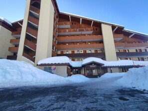 A multi-story hotel with balconies and a snow-covered entrance.