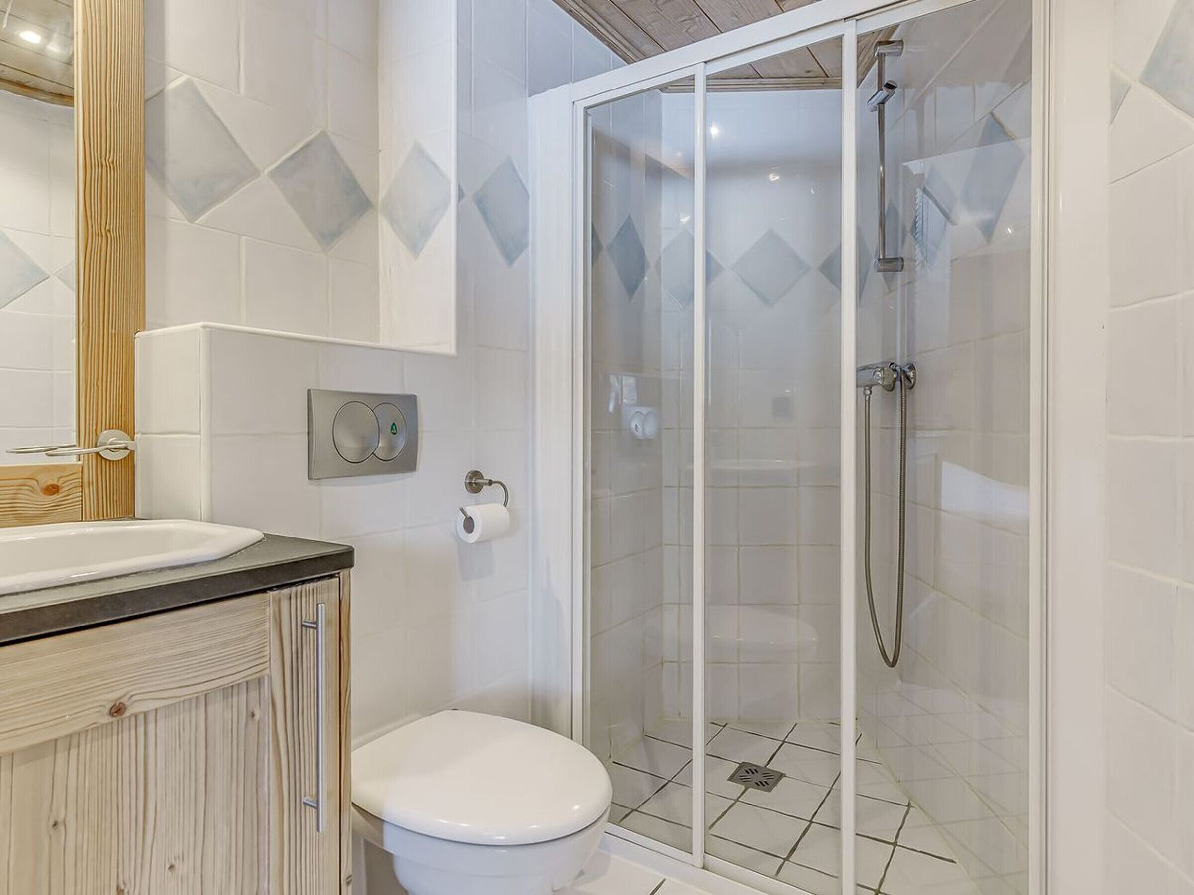 Un baño con inodoro, lavamanos y ducha con mampara de vidrio.