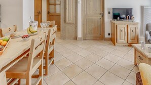 Una cocina acogedora con muebles de madera, una mesa de comedor dispuesta con frutas y vasos, un televisor y un armario con espejo.