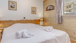 Una cama bien tendida con sábanas y toallas blancas, un cabecero de madera y una pared de madera con un letrero.