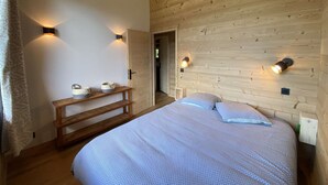 A wooden cabin bedroom with a bed, bedside tables, and wall-mounted lights.