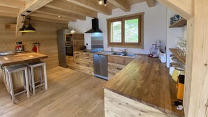 A kitchen with wooden beams, a large window, stainless steel appliances, and a wooden countertop.
