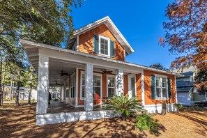 A two-story house with a covered porch, a small garden, and a clear blue sky. - 1282 Laurel Grove 3 Bedroom Home by RedAwning (Miramar Beach)