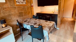Una cocina compacta con una mesa de comedor, sillas y una encimera negra.