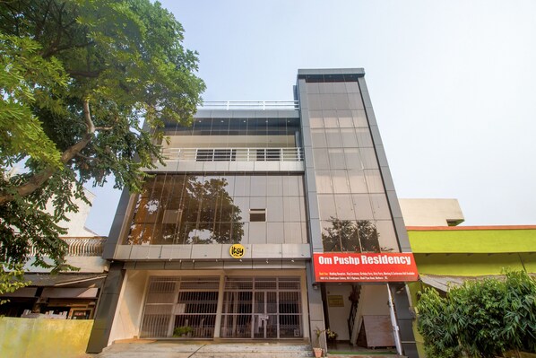 A modern building with a prominent sign for Om Pushp Residency.