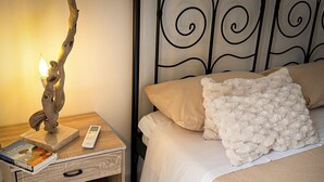 Een slaapkamer met een bed, kussens, een nachtkastje met een lamp en een afstandsbediening.