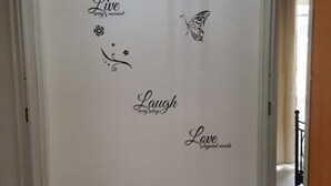 Een gang met decoratieve muurstickers met inspirerende zinnen en een vlinder.