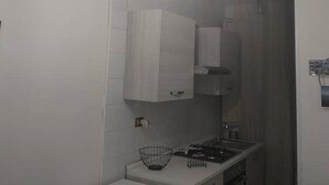 Een moderne keuken met witte kastjes, een aanrecht en een spoelbak. Daarboven hangen drie hanglampen.